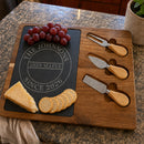Engraved charcuterie board styled with grapes, cheese, and crackers on a kitchen counter